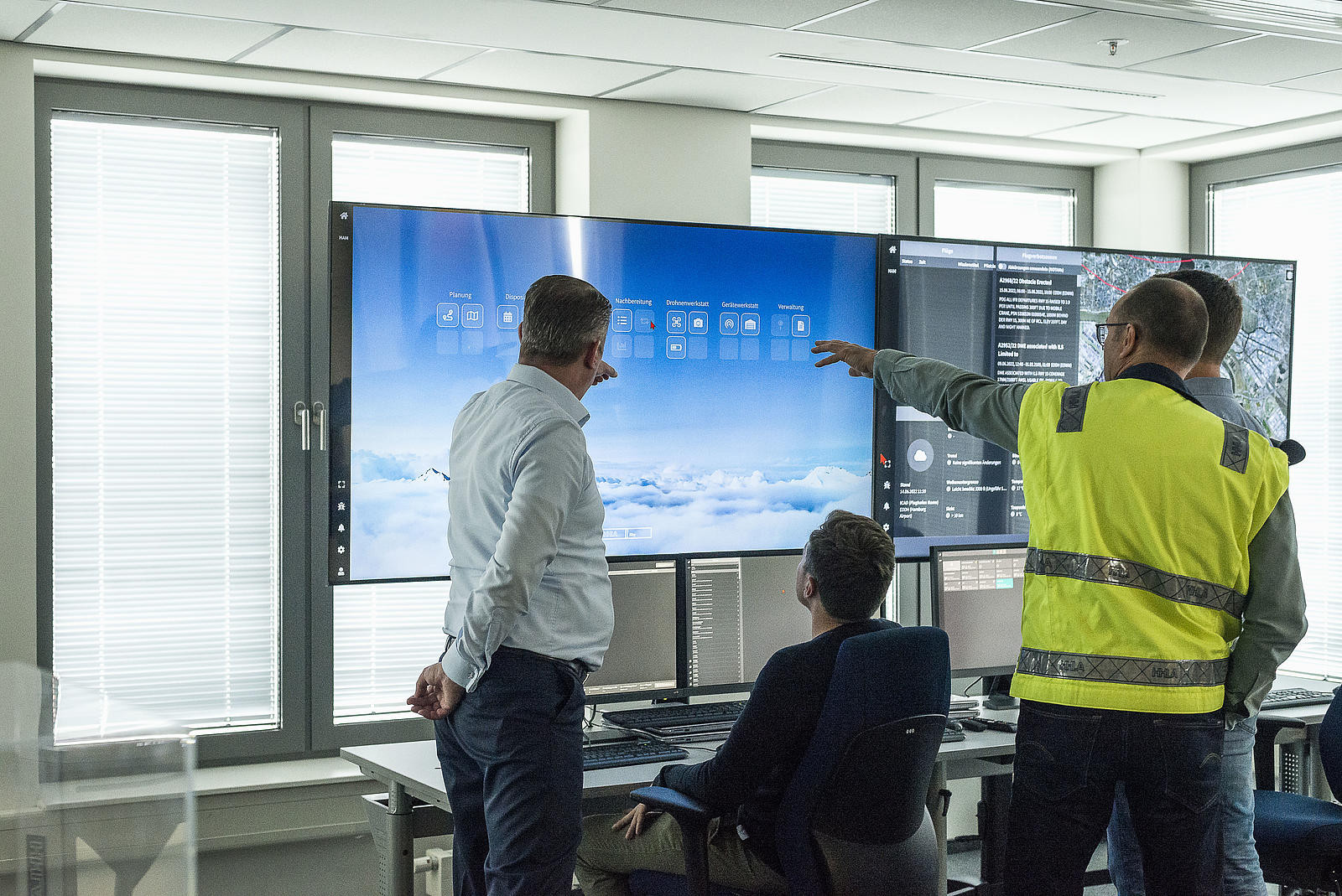 Group of four men looking at large screens