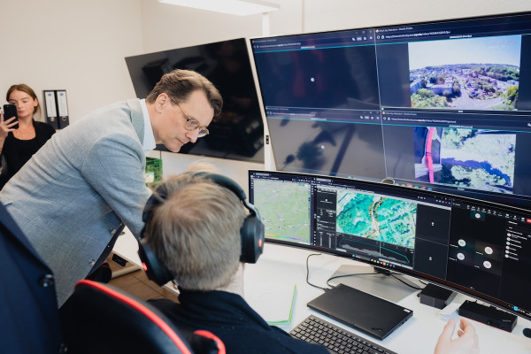 North Rhine-Westphalia's Minister President Hendrik Wüst in front of monitors at HHLA Sky’s Integrated Control Center. An operator keeps track of a drone's flight via video surveillance and drone tracking, among other things.